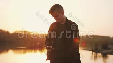 年轻人在海滩上美丽的日落时使用智能手机。 慢动作。